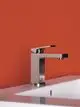 Waschbecken mit Ideal Standard Armatur, gefertigt aus Edelstahl, an orangefarbenem Wandhintergrund. Armatur hat eine moderne Form und befindet sich auf einem weißen Waschbecken.